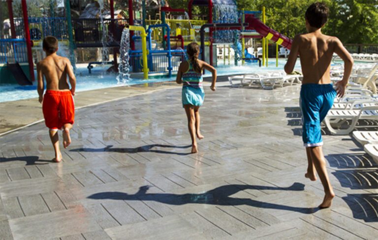 Three children running and playing on a splash pad with Life Floor safety surfacing installed.