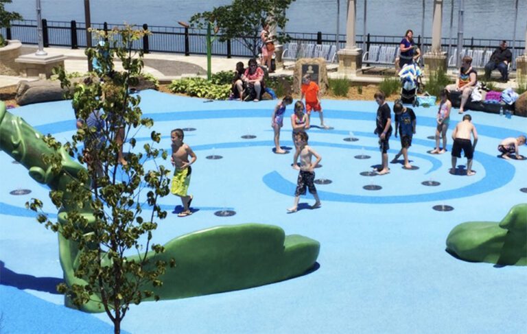 Group of kids playing on an outdoor wet play area with Flecks safety surfacing installed (blue).