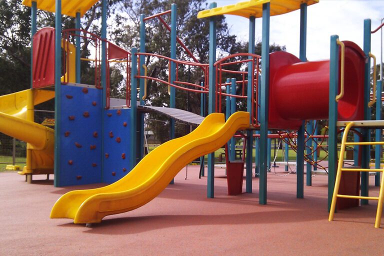 Red Play Flecks safety surfacing pictured with playground equipment.