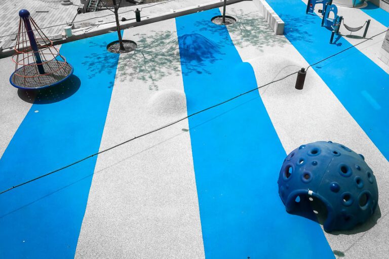 Overhead image of a playground with safety surface applied. mounds with blue and gray surfacing shown in the background.